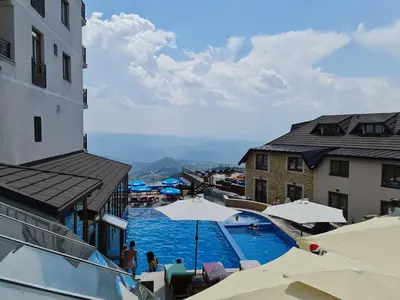 a view of a swimming pool with umbrellas and buildings at Apartman Sky Milmari L20 in Kopaonik