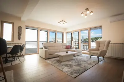 a living room with a couch and chairs and windows at Panorama LUX in Vrnjačka Banja