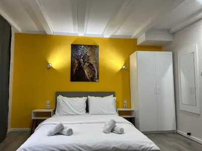 two beds in a room with a yellow wall at Vila Storia in Niš