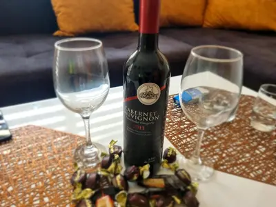 a bottle of wine and two wine glasses on a table at Apartman Miloš in Soko Banja