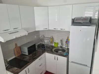 a kitchen with white cabinets and a sink and a refrigerator at Apartman Miloš in Soko Banja