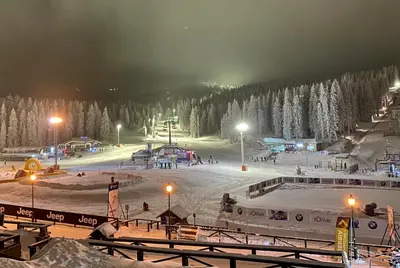 a snow covered ski slope with a ski resort at night at NevSki Apartments in Kopaonik
