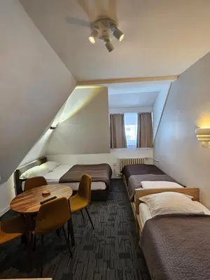 a hotel room with three beds and a table at NevSki Apartments in Kopaonik