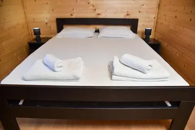 a bed in a room with two towels at Boja zalaska - drveni apartman in Jagodina