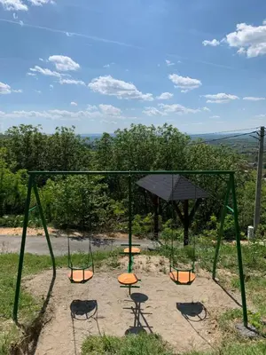 a swing set with chairs and a table at Boja zalaska - drveni apartman in Jagodina