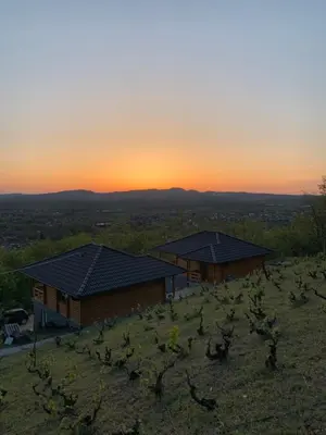 two houses on a hill with the sunset in the background at Boja zalaska - drveni apartman in Jagodina