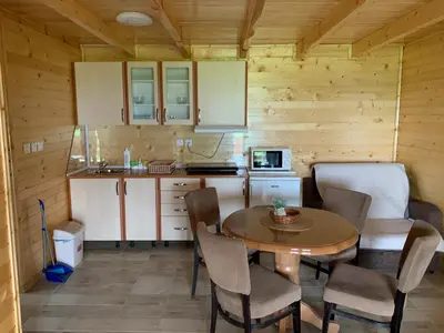 a kitchen with a table and chairs in a room at Boja zalaska - drveni apartman in Jagodina