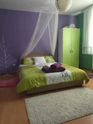 a bedroom with a green bed with a purple wall at Apartman i sobe Milica Vrnjacka Banja in Vrnjci