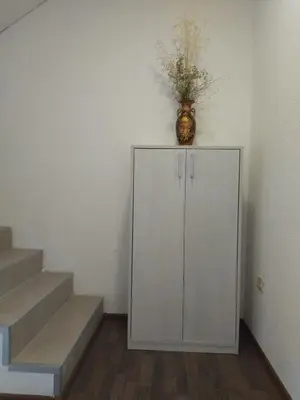 a white cabinet with a vase on top of it next to stairs at Apartman i sobe Milica Vrnjacka Banja in Vrnjci