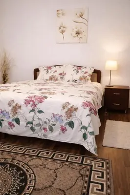 a bedroom with a bed with a floral bedspread at Apartman i sobe Milica Vrnjacka Banja in Vrnjci