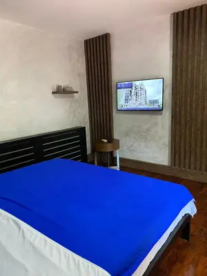 a bedroom with a blue bed and a tv on the wall at 32 in Jagodina