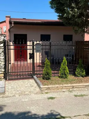 a black fence with a red door in front of a house at 32 in Jagodina