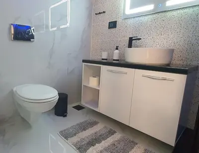a white bathroom with a toilet and a sink at Pansion Eden in Niš