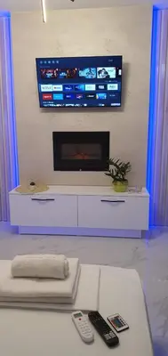 a living room with a tv on a wall with remote controls at Pansion Eden in Niš