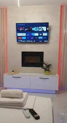 a living room with a tv on a wall at Pansion Eden in Niš