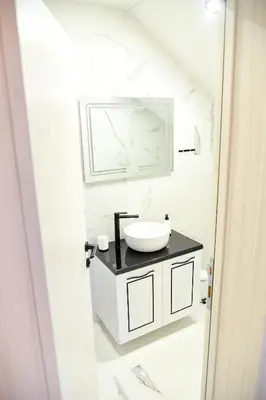a white bathroom with a sink and a mirror at Pansion Eden in Niš