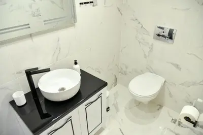a white bathroom with a sink and a toilet at Pansion Eden in Niš