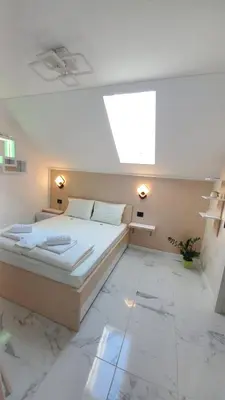 a bedroom with a large bed and a skylight at Pansion Eden in Niš