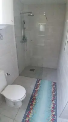 a bathroom with a shower with a toilet and a mosaic floor at Studio 