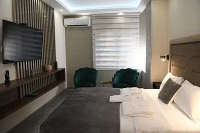 a hotel room with a bed and two green chairs at VS Exclusive Luxury Wellness & Spa Apartmani - Vrnjačka Banja in Vrnjačka Banja