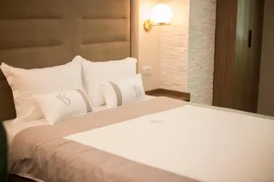 a bedroom with a white bed with white pillows at VS Exclusive Luxury Wellness & Spa Apartmani - Vrnjačka Banja in Vrnjačka Banja