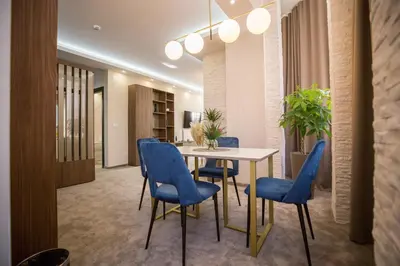 a dining room with a table and blue chairs at VS Exclusive Luxury Wellness & Spa Apartmani - Vrnjačka Banja in Vrnjačka Banja