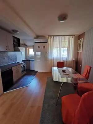 a living room with a glass table and a kitchen at Apartman Stanimirović in Zaječar