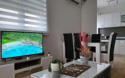 a living room with a television on a white table at Apartman TEJA DELUXE in Vrnjačka Banja