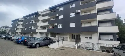 a large building with cars parked in a parking lot at Apartman TEJA DELUXE in Vrnjačka Banja