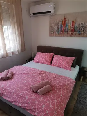 a bedroom with a pink bed with two pillows at Nikolic apartment in Niš