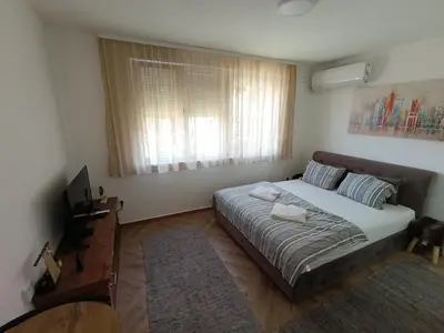 a bedroom with a large bed and a window at Nikolic apartment in Niš