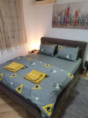 a bed with a blue comforter with yellow pillows at Nikolic apartment in Niš