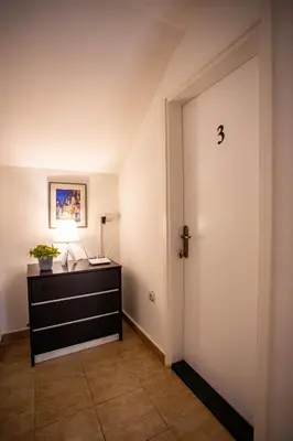 a hallway with a door and a dresser with a lamp at Paris Night Private Parking in Niš