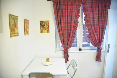a window with red checkered curtains in a room at Paris Night Private Parking in Niš