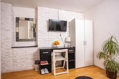 a room with a desk and a tv on a brick wall at Paris Night Private Parking in Niš