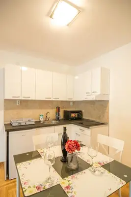 a kitchen with white cabinets and a table with wine glasses at Apartmani Central 7 & Free parking in Vrnjačka Banja