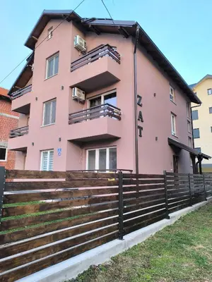 a pink building with a fence in front of it at Apartmani ZAT in Soko Banja