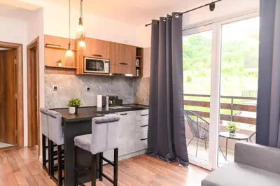 a kitchen with a bar with chairs and a balcony at Apartmani ZAT in Soko Banja