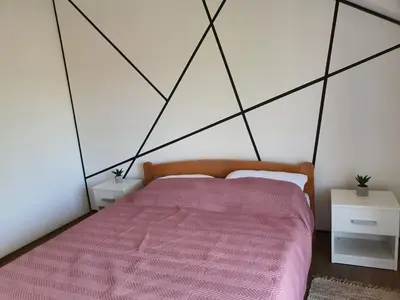 a bedroom with a bed with a pink comforter at Apartman Buena Vista in Soko Banja