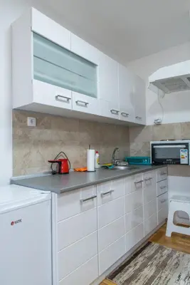a kitchen with white cabinets and a sink at Apartmani Central 8 & Free parking in Vrnjačka Banja