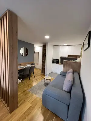 a living room with a blue couch and a kitchen at NeNi Apartman in Vrnjačka Banja