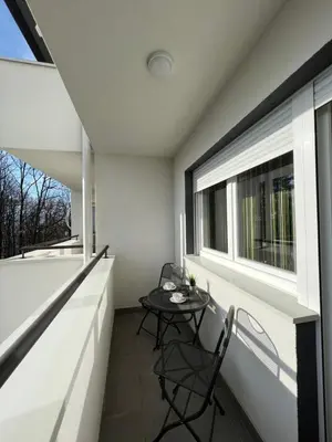 a balcony with a table and chairs and a window at NeNi Apartman in Vrnjačka Banja
