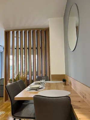 a dining room with a table and chairs and a mirror at NeNi Apartman in Vrnjačka Banja