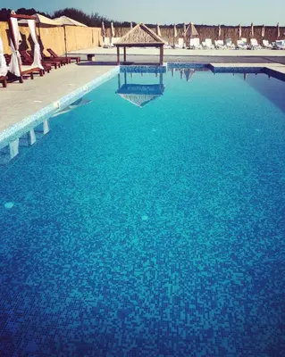 a large pool of blue water with chairs and a gazebo at STD JOVIC sa bazenom in Lebane