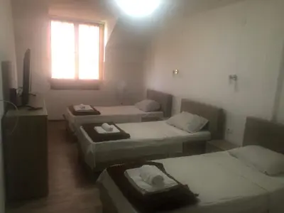 a room with three beds and a television and a window at STD JOVIC sa bazenom in Lebane