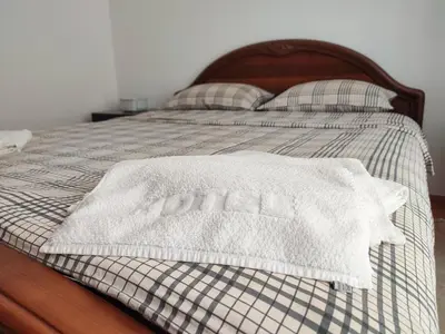 a bed with a white blanket and pillows on it at MILA city center-free parking in Vranje