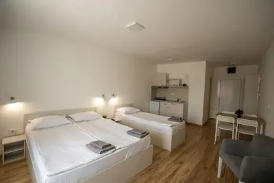 a white bedroom with two beds and a chair at Milutinn-Kruška-Magnolija in Soko Banja