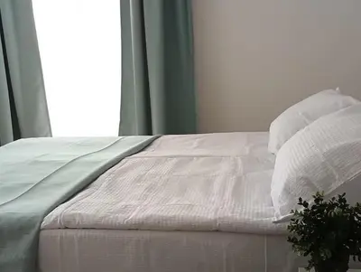 a bed with white sheets and pillows next to a window at Milutinn-Trešnja in Soko Banja
