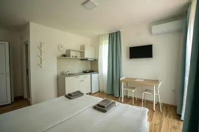 a white bedroom with a bed and a small table at Milutinn-Trešnja in Soko Banja