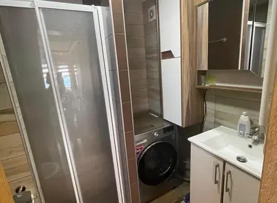 a small bathroom with a shower and a washing machine at Milmari Resort Lux H-1 in Kopaonik